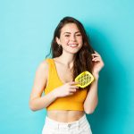 how-much-hair-loss-is-normal--in-a-day-beautiful-young-woman-smiling-brushing-healthy-long-hair