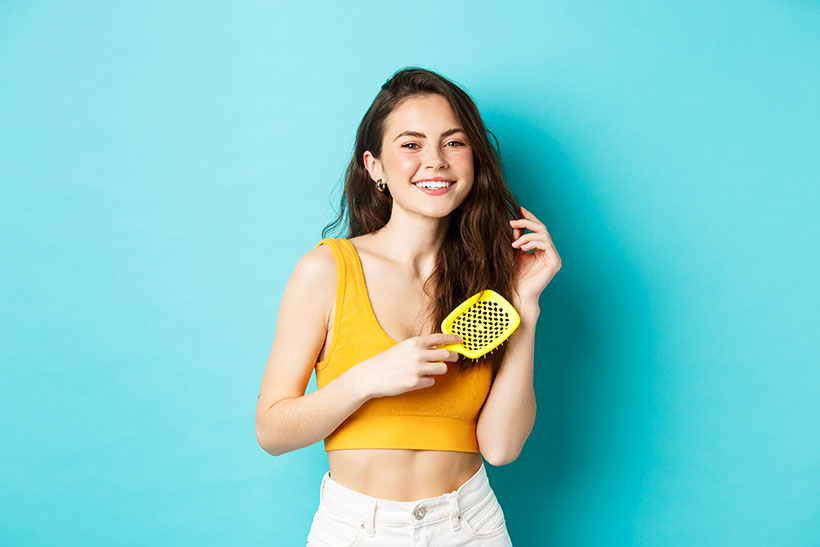 how-much-hair-loss-is-normal--in-a-day-beautiful-young-woman-smiling-brushing-healthy-long-hair